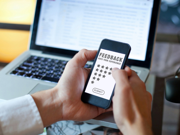 A person holding a mobile phone with a review screen with different options from 5 stars to 1 star