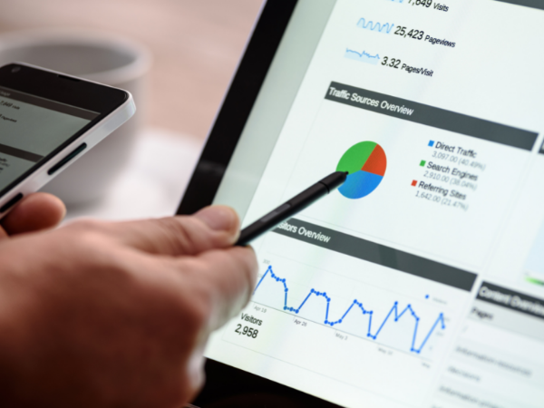 A close up of a screen showing analytics and web traffic data and a close up of a hand pointing at the data.