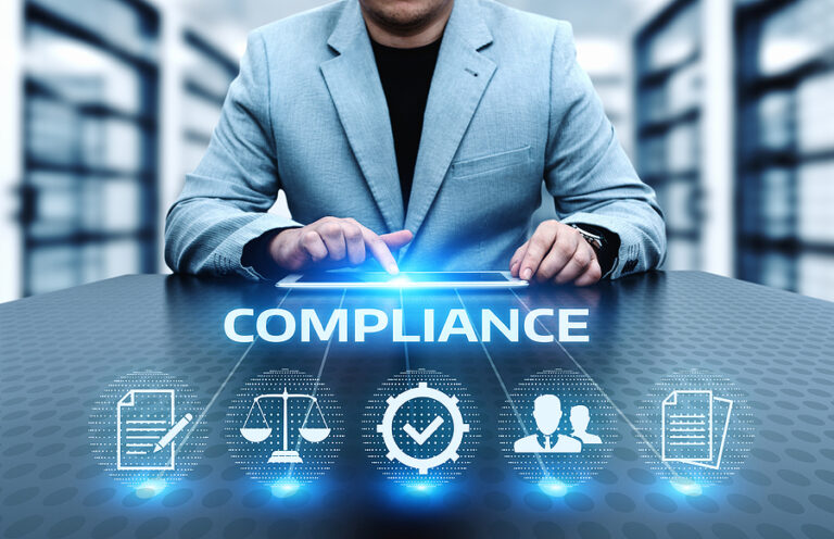 A business professional sits at a desk and uses a tablet while the word COMPLIANCE and related icons float in the foreground.
